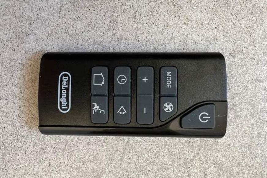 Die Fernbedienung der De’longhi PAC EX105 Silent mobilen Klimaanlage liegt auf dem Gerät.